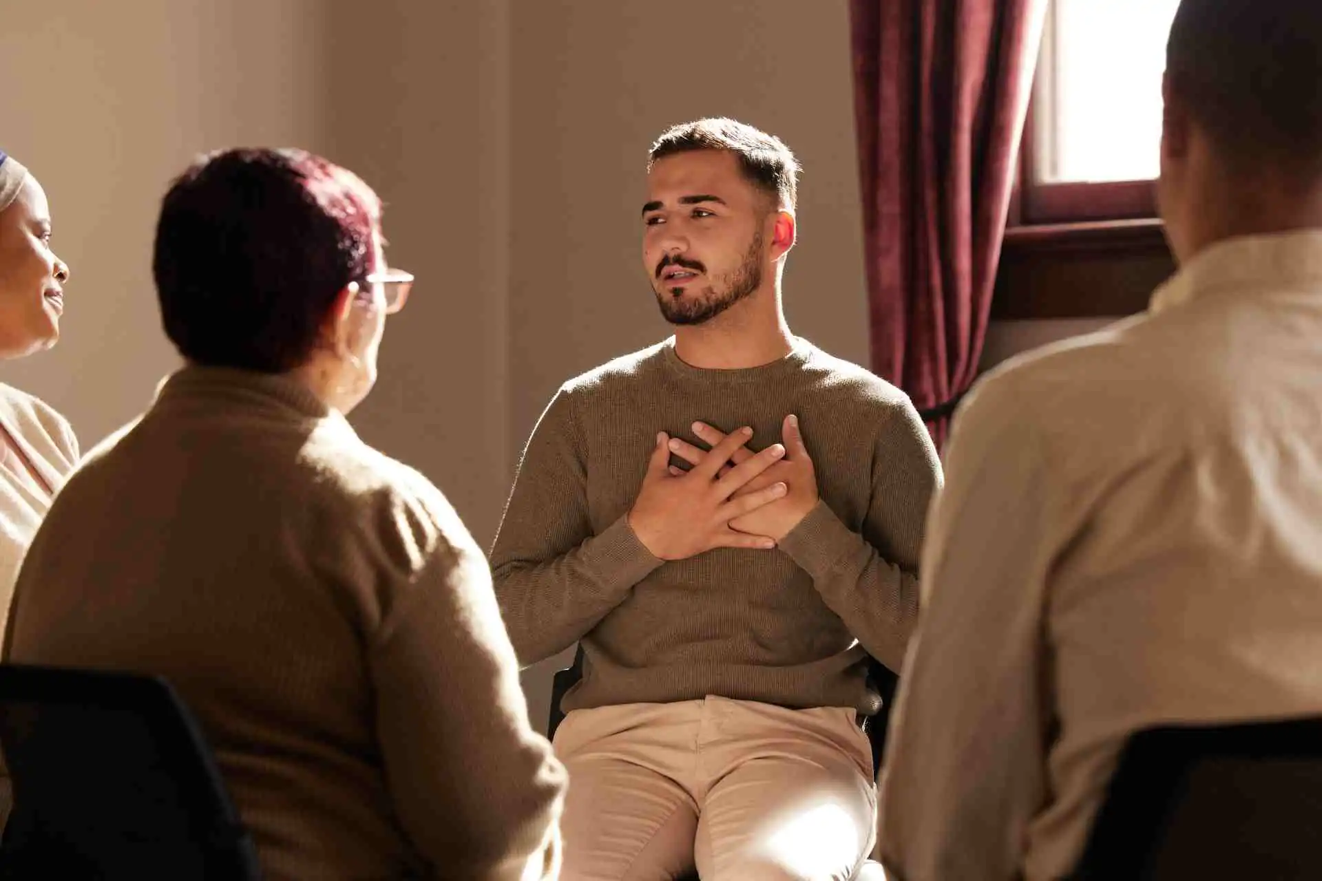Man speaking openly during group therapy in inpatient addiction treatment