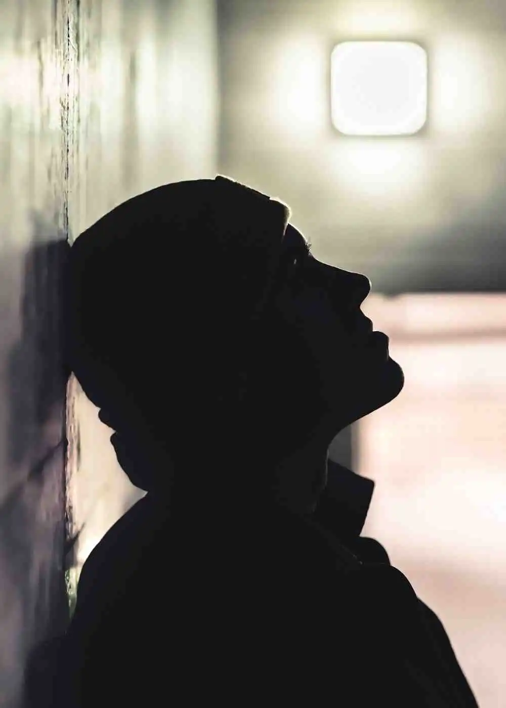 Silhouette of a person leaning against a wall in distress, representing early signs of drug addiction