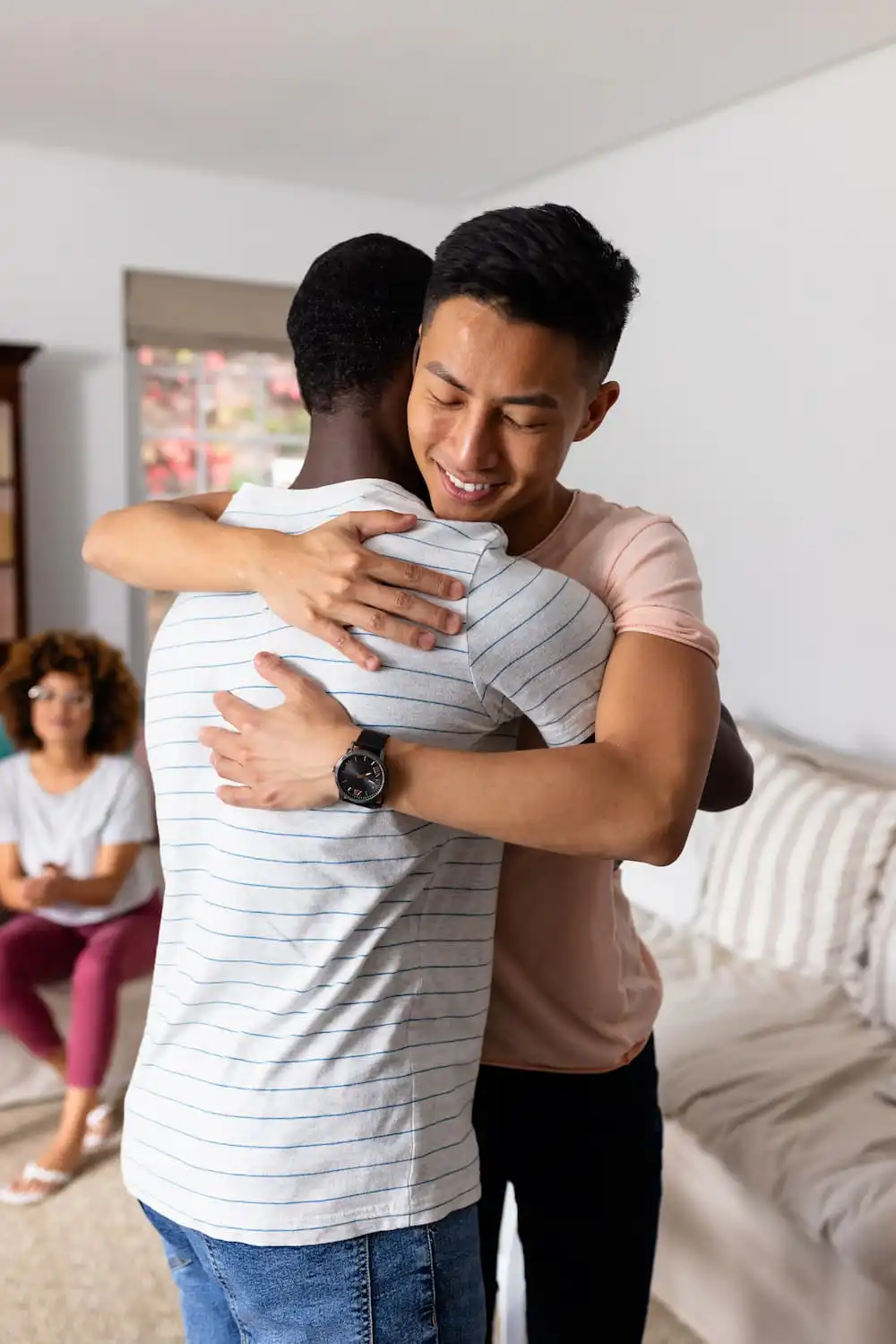 Two men hugging in a group therapy session for addiction treatment